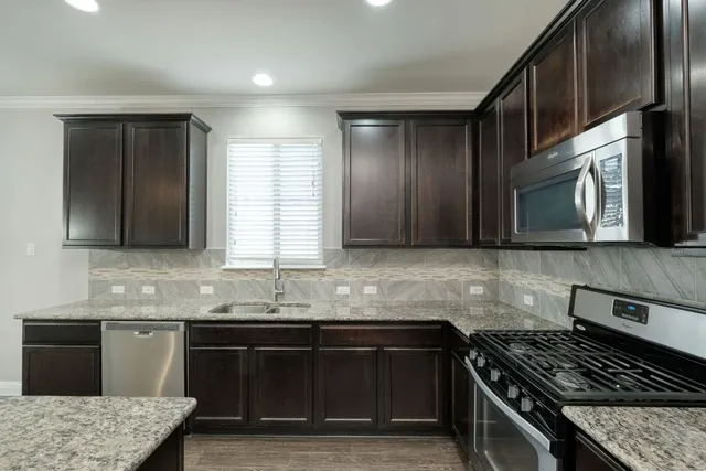 a kitchen with stainless steel appliances granite countertop a sink stove and cabinets