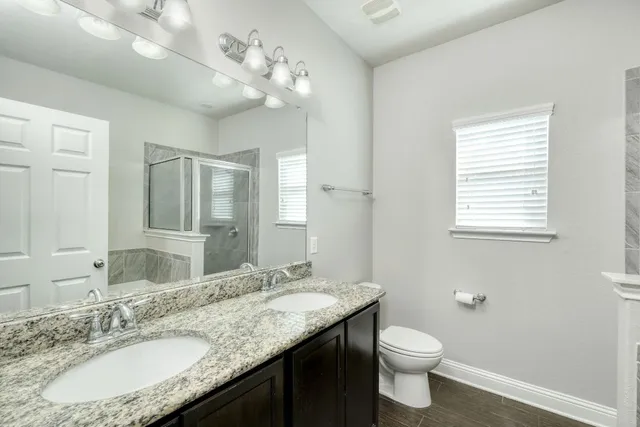 a bathroom with a granite countertop sink a toilet and a mirror