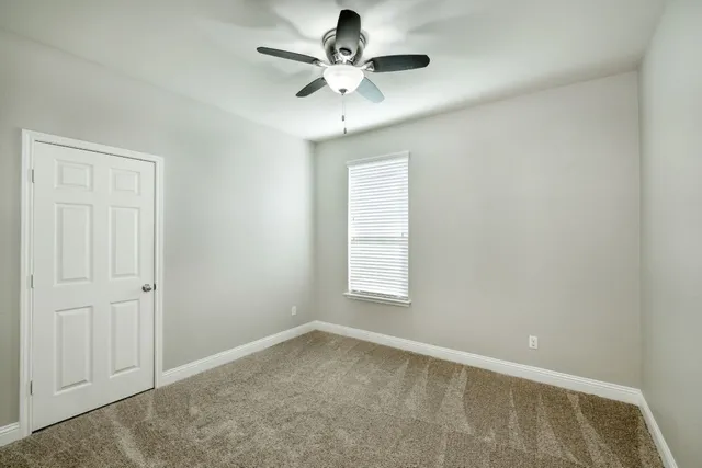 an empty room with a window and a ceiling fan