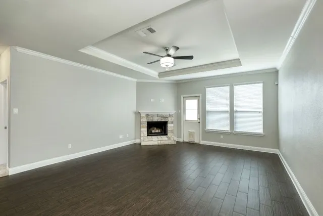 an empty room with wooden floor fireplace and windows