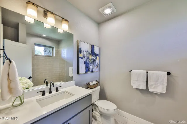 a bathroom with a sink vanity mirror and toilet