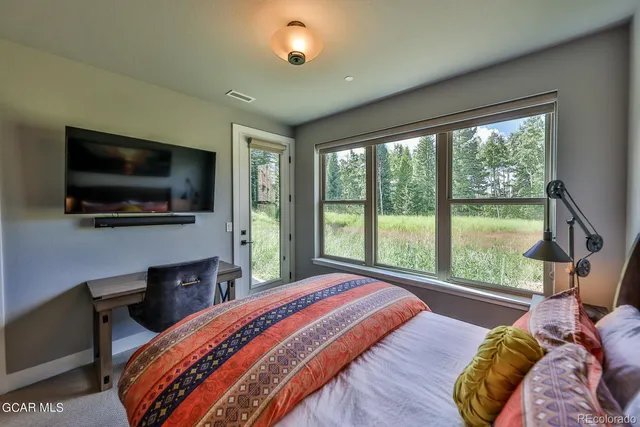 a bedroom with a bed a flat screen tv and a large window