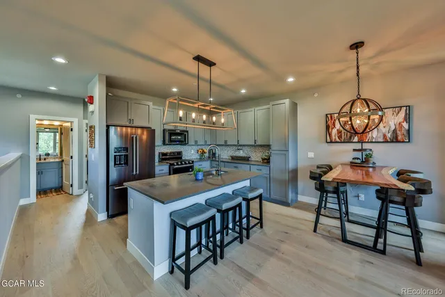 a kitchen with stainless steel appliances granite countertop sink refrigerator dining table and chairs