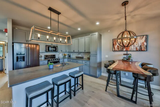 a kitchen with stainless steel appliances kitchen island granite countertop a table chairs and a refrigerator