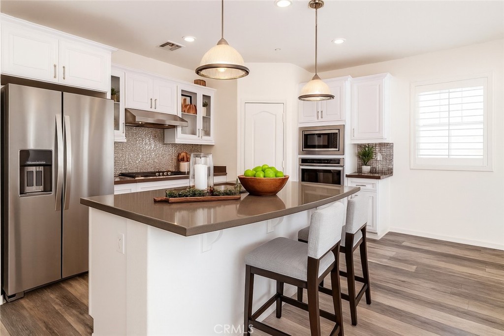 24536 Acadia Drive Corona, CA 92883 - Photo 7 of 40 a kitchen with kitchen island a large counter top space appliances and cabinets