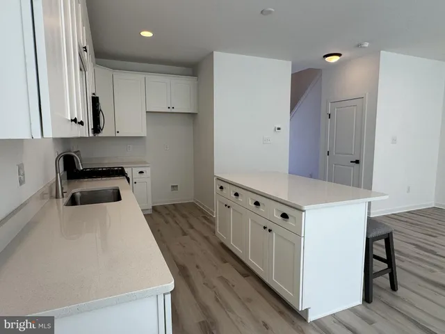 a kitchen that has a lot of white cabinets and wooden floor