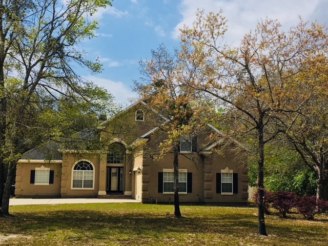 96525 Chester Road Yulee, FL 32097 - Photo 1 of 35 a front view of a house with a garden