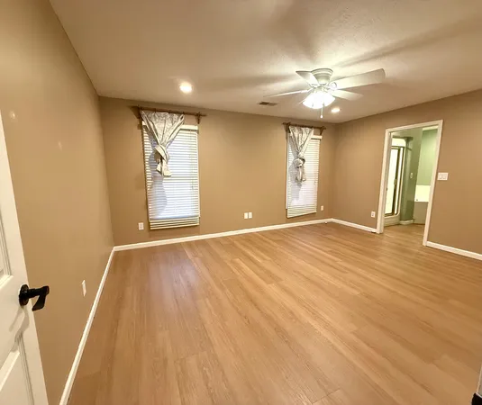 a view of an empty room with wooden floor and a window