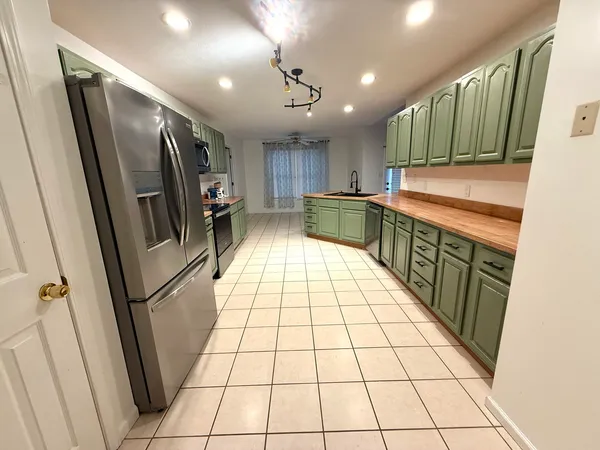 a kitchen with stainless steel appliances granite countertop a refrigerator a sink and wooden cabinets