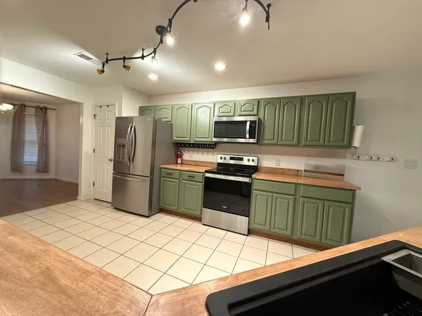 a kitchen with stainless steel appliances kitchen island granite countertop a refrigerator and a stove top oven