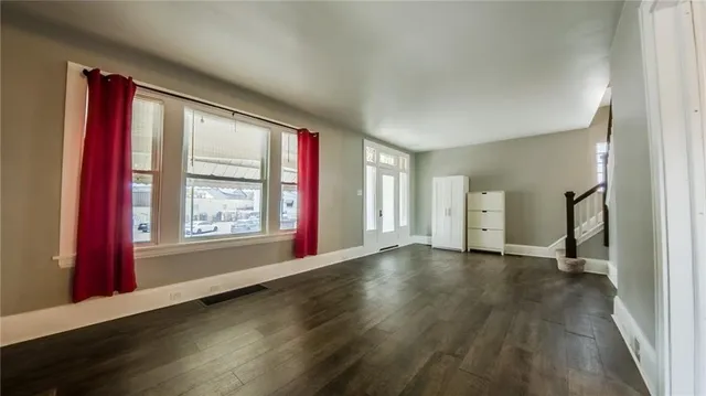 a view of an empty room with window and wooden floor