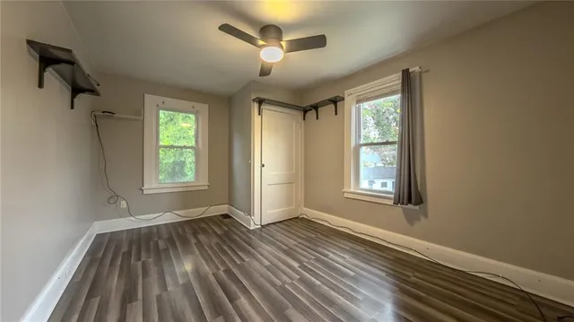 a view of an empty room with a window and wooden floor