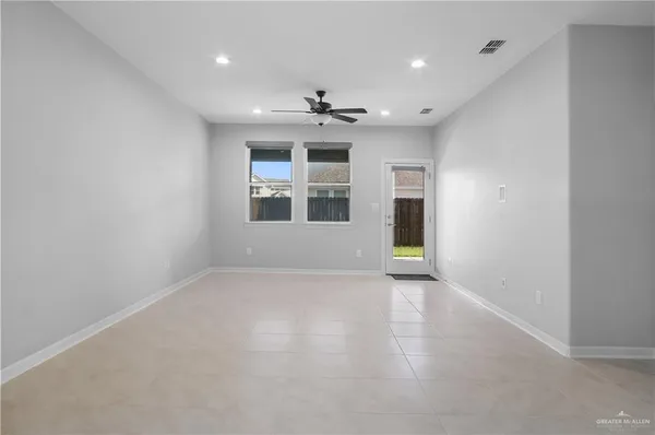 an empty room with chandelier fan and windows