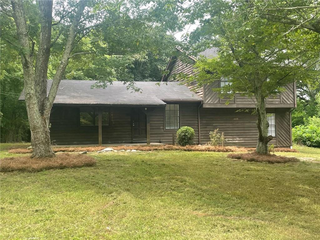 a front view of a house with a garden and tree