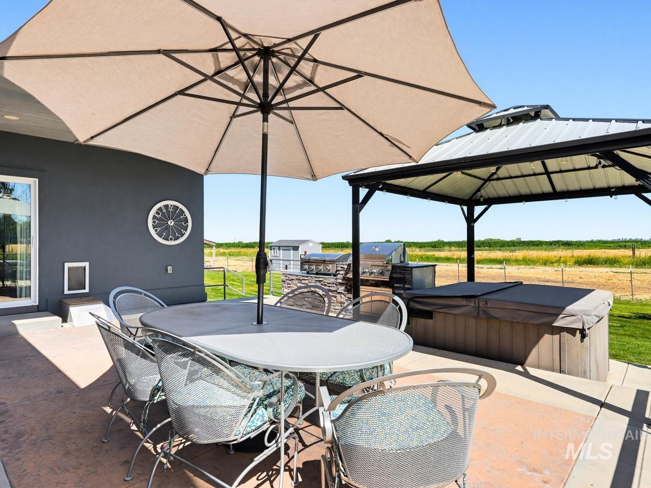 4950 West Columbia Road Nampa, ID 83687 - Photo 41 of 50 Spacious concrete patio featuring a built-in outdoor kitchen with stone accents, a covered hot tub area, and direct access to the interior