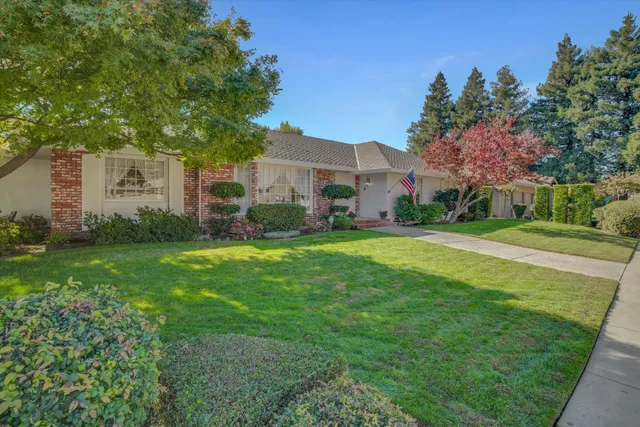 a view of a house with a big yard and large trees