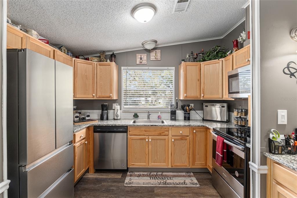 1727 Hilton Head Boulevard Lady Lake, FL 32159 - Photo 6 of 39 a kitchen with a sink a stove cabinets and a window