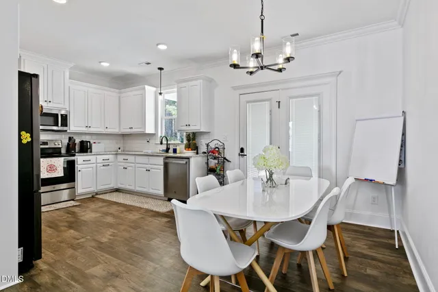 a kitchen with stainless steel appliances kitchen island granite countertop a dining table chairs and white cabinets