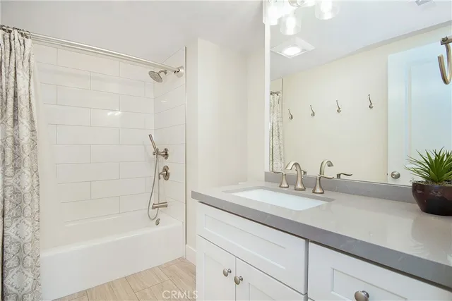 a bathroom with a granite countertop sink a mirror a bathtub and shower