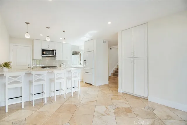 a large white kitchen with cabinets and chairs