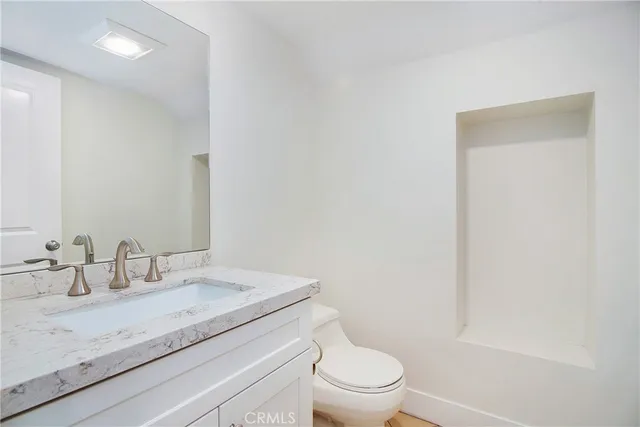 a bathroom with a granite countertop sink a toilet and a mirror