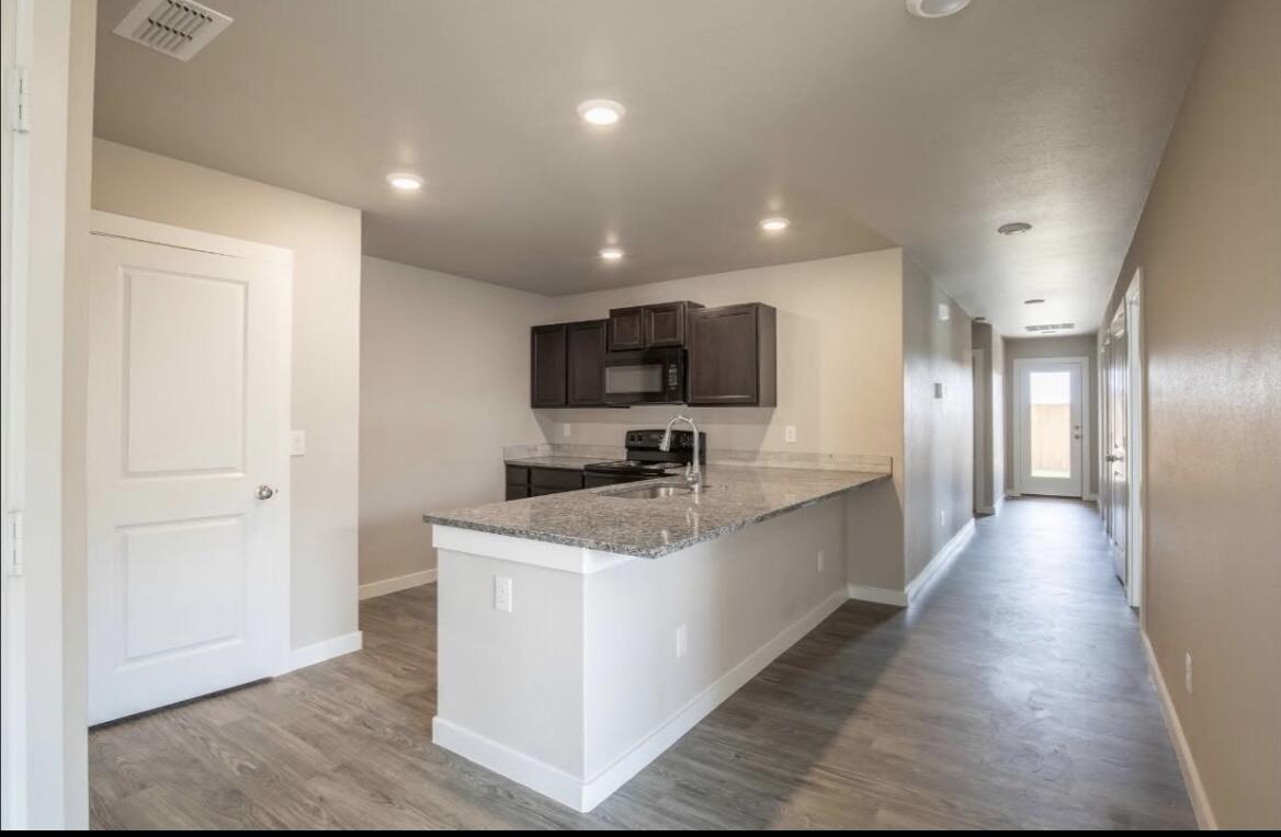 14413 Avenue X, Unit A Lubbock, TX 79423 - Photo 4 of 9 a large kitchen with stainless steel appliances granite countertop a sink a stove top oven a counter space and cabinets