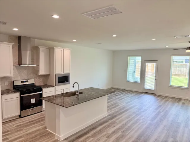 a kitchen with granite countertop a sink stove and cabinets