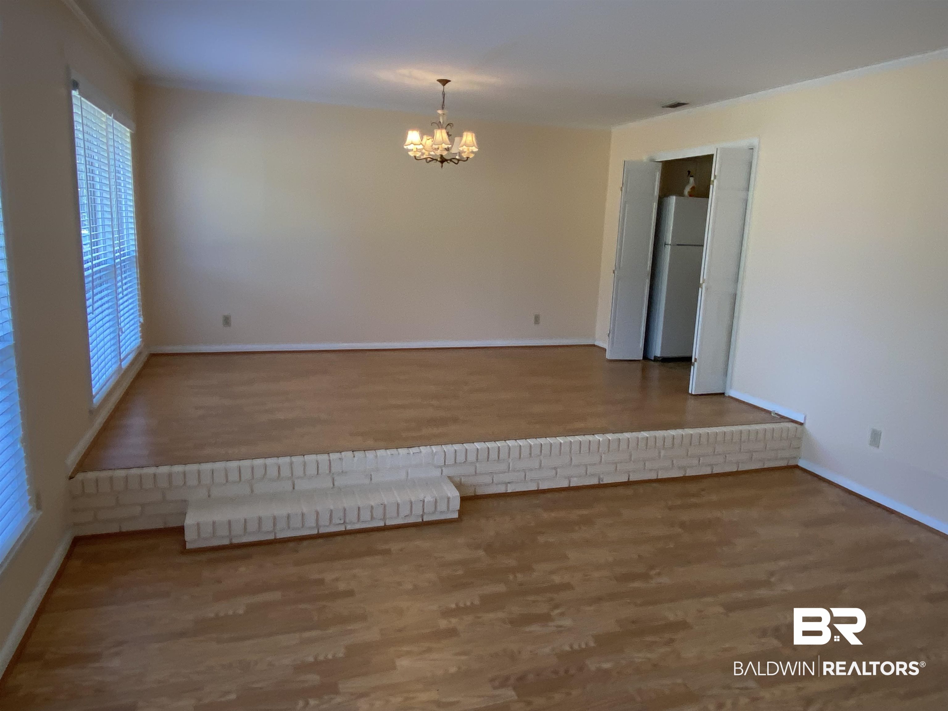 106 Terry Drive Brewton, AL 36426 - Photo 3 of 25 Empty room featuring wood finished floors and a chandelier with step down to the living room.