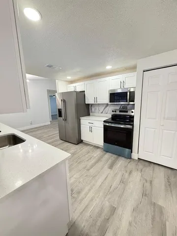 a large white kitchen with cabinets a sink and dishwasher
