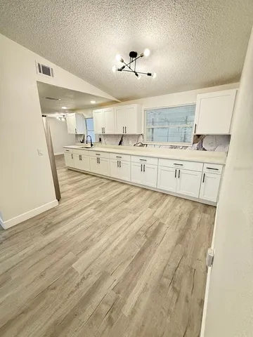 an empty room with wooden floor cabinet and windows