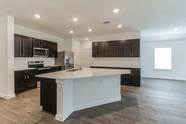 a large kitchen with stainless steel appliances a large counter top a stove a microwave a sink and a refrigerator