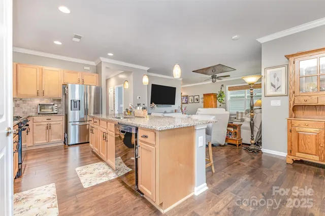 a view of kitchen with stainless steel appliances kitchen island granite countertop a stove and white cabinets