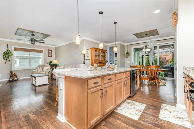 a open kitchen with stainless steel appliances granite countertop a stove a sink a dining table and chairs with wooden floor