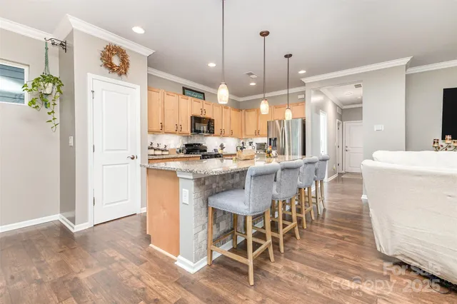 a kitchen with stainless steel appliances kitchen island granite countertop a table chairs and a refrigerator