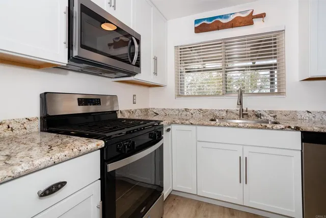 a kitchen with granite countertop cabinets stainless steel appliances and a sink