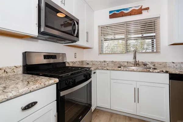 a kitchen with granite countertop cabinets stainless steel appliances and a sink