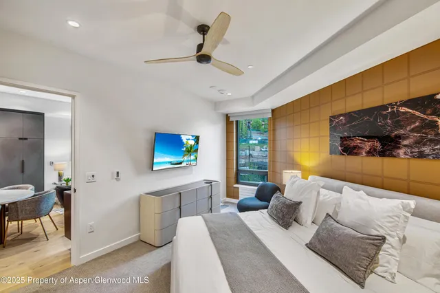 a bedroom with a bed a couch and a flat screen tv