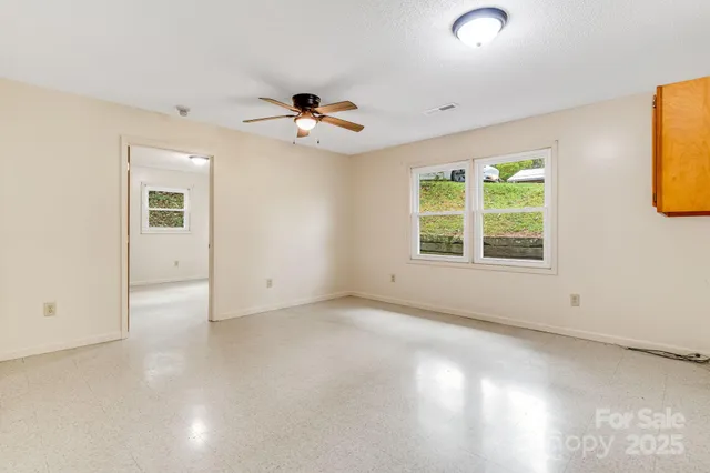an empty room with windows and ceiling fan