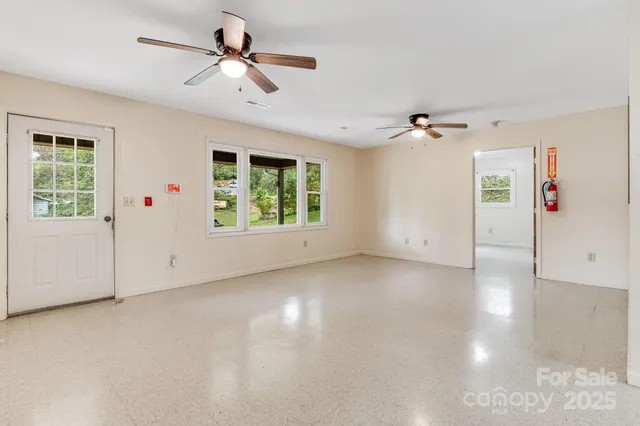 an empty room with windows and ceiling fan