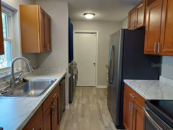 a kitchen with granite countertop stainless steel appliances a sink and a refrigerator