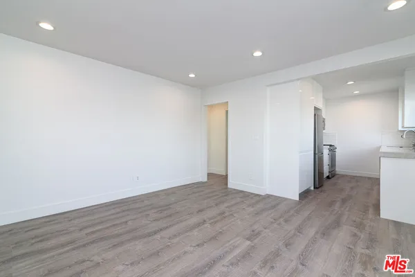 a view of a big room with wooden floor and a kitchen
