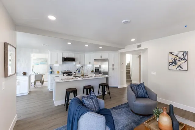 a living room with furniture kitchen view and a wooden floor