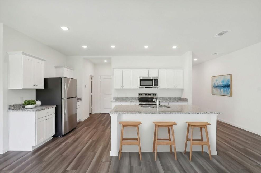 a kitchen with stainless steel appliances kitchen island granite countertop a table chairs stove and refrigerator