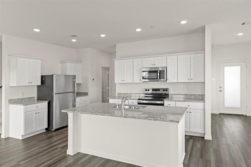 1508 Lake Alpine Trail Anna, TX 75409 - Photo 9 of 40 a large kitchen with stainless steel appliances granite countertop a stove a sink a refrigerator and white cabinets granite countertops with wooden floor