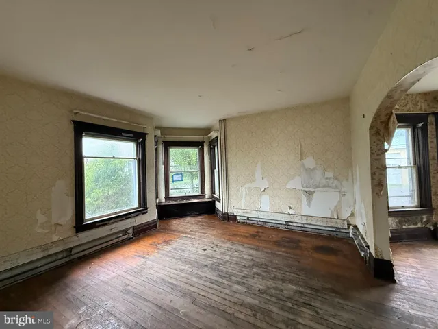 a view of an empty room with window and wooden floor