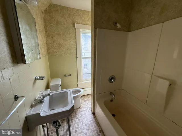 a bathroom with a tub sink and mirror