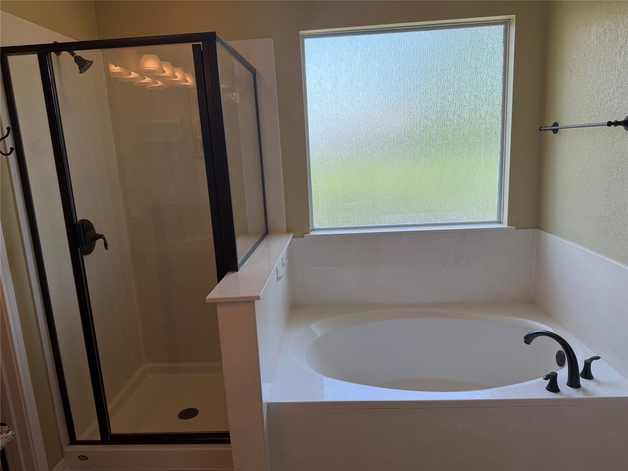 3021 Grand Mission Way Pflugerville, TX 78660 - Photo 26 of 31 A spacious bathroom presents a built-in soaking tub beneath a privacy window and a glass-enclosed shower stall.