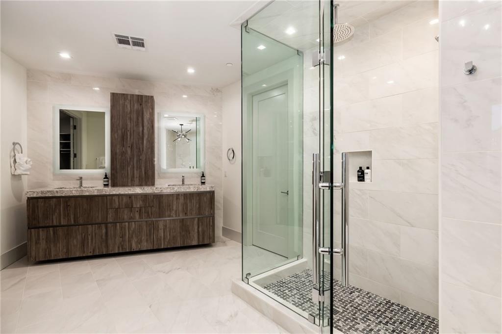 3107 Peachtree Road Northeast, Unit 1803 Atlanta, GA 30305 - Photo 23 of 45 a bathroom with a mirror a double vanity sink and glass door