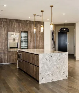 a kitchen with stainless steel appliances kitchen island granite countertop a refrigerator a oven and a wooden floors