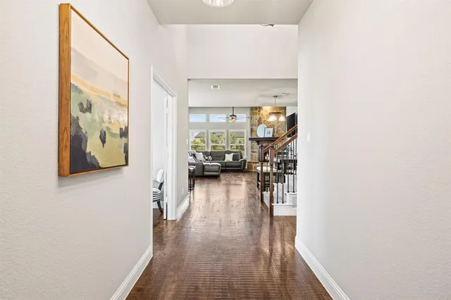 a view of a hallway with wooden floor and a living room